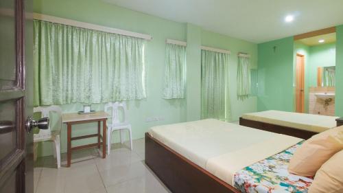 a bedroom with two beds and a table in it at CM Apartelle Iloilo International Airport by RedDoorz in Cabatuan