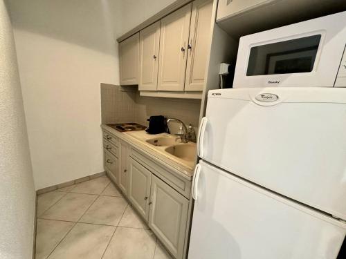 une cuisine avec un réfrigérateur blanc et un évier dans l'établissement 242 Cannes La Croisette - Studio au calme coté jardin, à Cannes