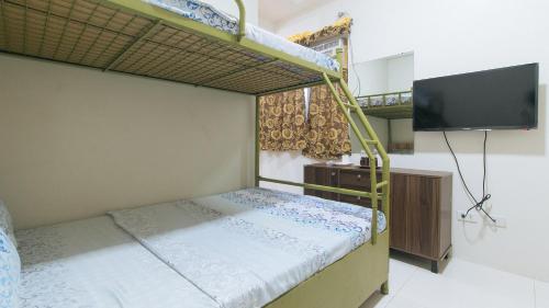 a bedroom with two bunk beds and a flat screen tv at CM Apartelle Iloilo International Airport by RedDoorz in Cabatuan