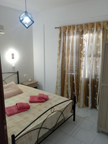 a bedroom with a bed with two red pillows on it at Akrogiali Rooms & Studios in Drymonas