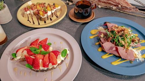 three plates of food on a table with strawberries on them at BnA WALL in Tokyo