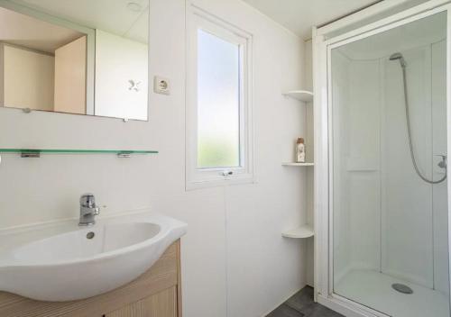 un bagno bianco con lavandino e doccia di Mobil-home de Laura et Angélique au camping ''Le Neptune'' jusqu'à 4 personnes ad Argelès-sur-Mer