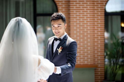 a man in a tuxedo standing next to a bride at HUALUXE Yangjiang City Center in Yangjiang