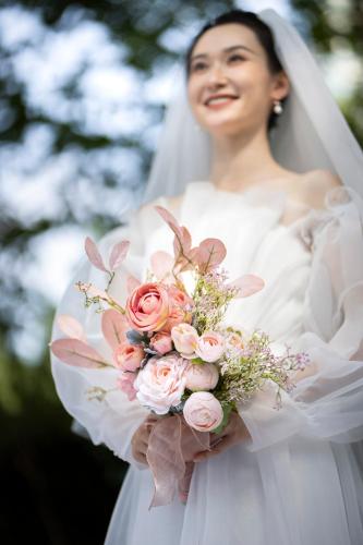 a bride holding a bouquet of pink roses at HUALUXE Yangjiang City Center in Yangjiang