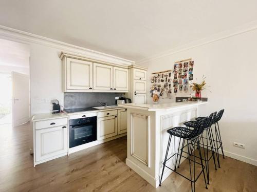 une cuisine avec des placards blancs et des tabourets noirs dans l'établissement appartement T3 golf, à Mallemort