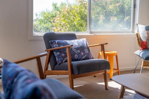 a living room with a chair and a pillow at Syds Place A 70s retro beach house Free WIFI in Goolwa South