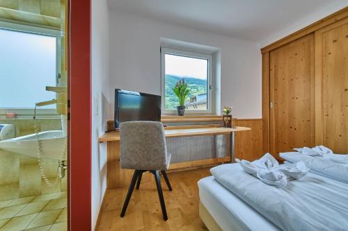 a bedroom with a desk with a computer and a bed at Platzhirsch Rooms - B&B - SELF CHECK-IN in Piesendorf