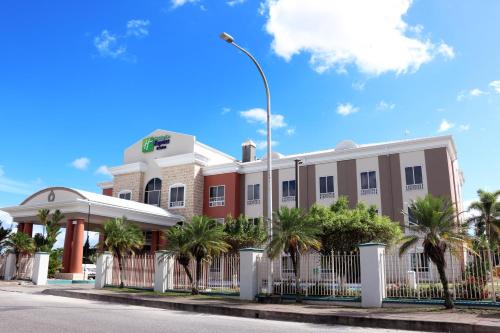 a building with a fence in front of a street at Holiday Inn Express Trincity by IHG in Piarco