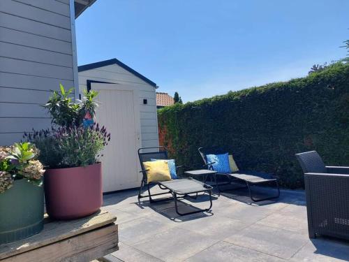 a patio with two chairs and a bench and a fence at Stelle Maris, Nice place in Heinkenszand, 2 bedrooms, outdoor swimming pool, WIFI smart TV and privacy in Heinkensand