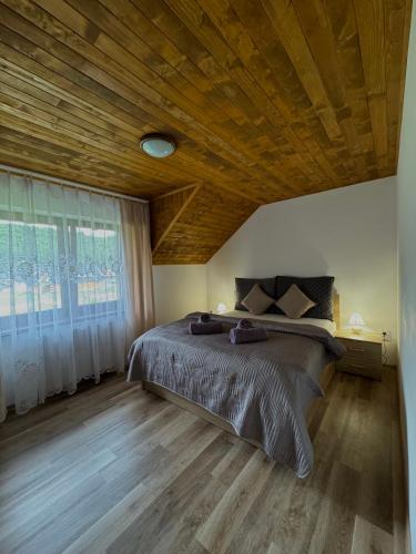a bedroom with a large bed and a wooden ceiling at Chata Fir in Valča