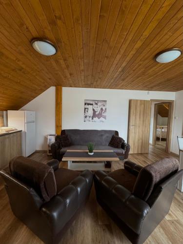 a living room with leather furniture and a wooden ceiling at Chata Fir in Valča