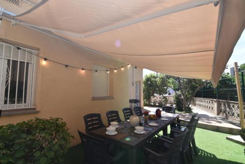 a table and chairs under an umbrella on a patio at RNET - MT - Casa Can Carles in Roses