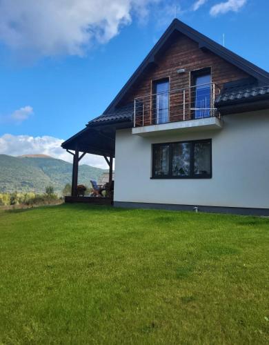 a house with a balcony and a grass yard at Panskiemisie Domki Całoroczne sauna jacuzzi in Wetlina