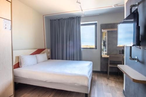 a hotel room with a bed and a television at ibis budget Toulouse Labège in Labège