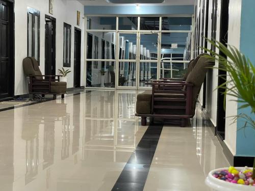 a lobby with chairs and a bowl of fruit on the floor at Nilastay emirates in Kazhakuttam