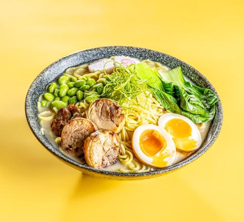a bowl of noodles and eggs on a yellow background at AG Hotel in Abu Dhabi