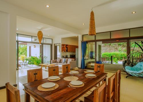 a kitchen and living room with a wooden table and chairs at Luxurious Pool villa with great sea view in Koh Phangan