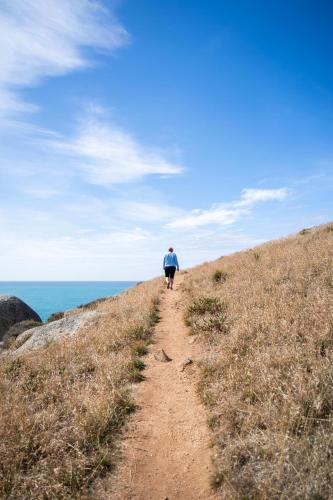 a person walking down a dirt road near the ocean at Cerca Del Agua family and pet friendly in Encounter Bay