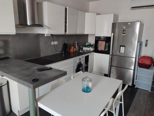 Il comprend une cuisine équipée d'une table blanche et d'un réfrigérateur. dans l'établissement Appartement saint loup, à Marseille