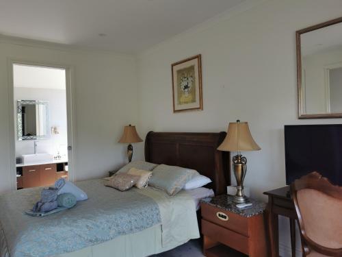 a bedroom with a bed and a desk and a mirror at Gypsy Creek Retreat in Labertouche