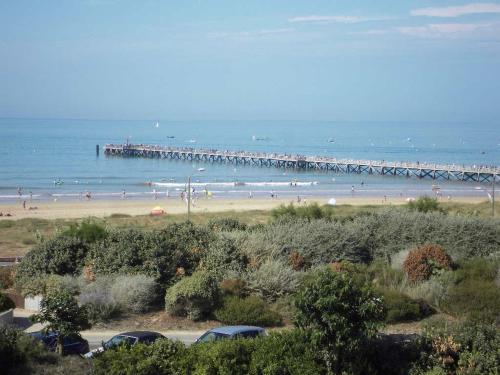 une plage avec des gens dans l'eau et une jetée dans l'établissement Appartement vue mer, à Saint-Jean-de-Monts