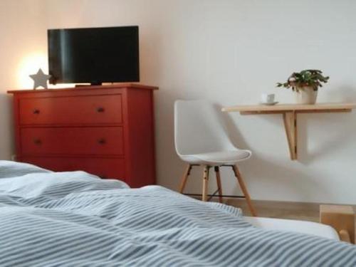 ein Schlafzimmer mit einem Bett, einem Stuhl und einem TV in der Unterkunft Gästezimmer Haus Tulpenstraße in Elsfleth