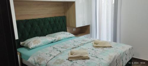 a bed with a green headboard and two towels on it at CENTAR CEPERKOVIC in Vrnjačka Banja