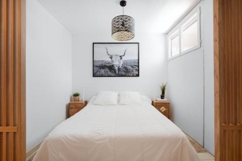 - une chambre dotée d'un lit blanc avec une photo de cerf sur le mur dans l'établissement AS23993 - P2 Centre ville - parking privé et wifi, au Grau-du-Roi
