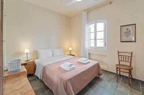 a bedroom with a bed and a chair and a window at Summer Retreat, 50m from Gialia Beach by Explore Andros in Andros