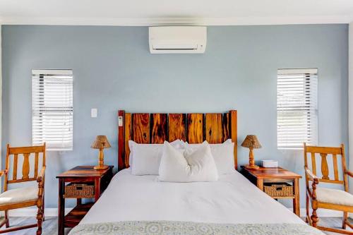 ジョージにあるThe Halfway House @ Kingswood Golf Estateのベッドルーム1室(大きな白いベッド1台、椅子2脚付)