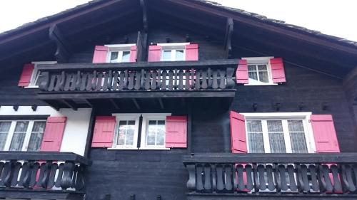 a building with pink and white windows and a balcony at Hotel Burgener in Saas-Fee