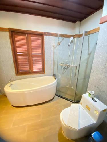 a bathroom with a tub and a shower and a toilet at Luangprabang Villa Kee Lee in Luang Prabang