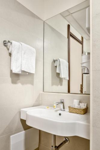 a white bathroom with a sink and a mirror at Hotel Italia in Cagliari