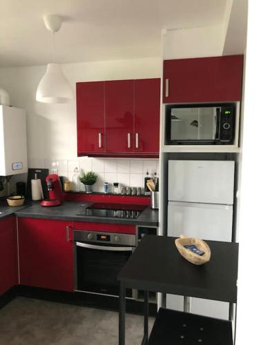 - une cuisine avec des placards rouges et une cuisinière noire dans l'établissement Appartement RDC quartier calme, à Saint-Dizier