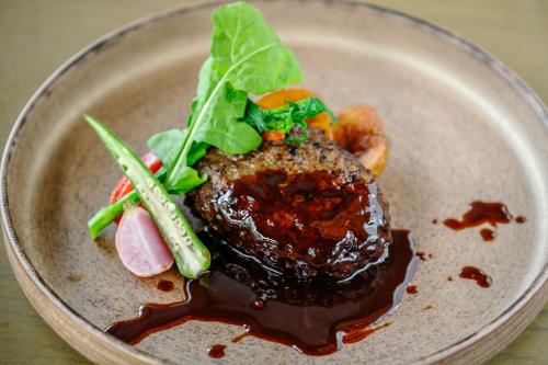 a plate of food with meat and vegetables on it at Glamday Style Okinawa Yomitan Hotel & Resort in Yomitan