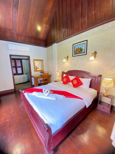 a bedroom with a large bed with red pillows at Luangprabang Villa Kee Lee in Luang Prabang