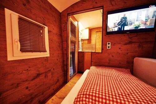 a small room with a tv and a bed in it at Schäferwagen Merino in Gräfenberg