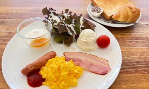 a plate of breakfast food with eggs sausage and vegetables at Glamping Resort Yokabushi in Ishigaki Island