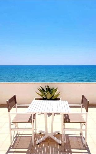 a white table and chairs with the ocean in the background at Hotel Acquamarina in Donnalucata
