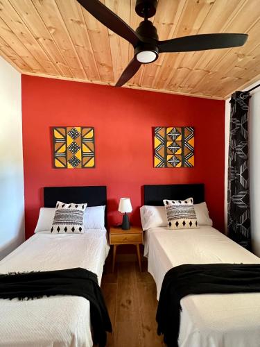 two beds in a room with a red wall at Hacienda la Yerbabuena in Cádiz
