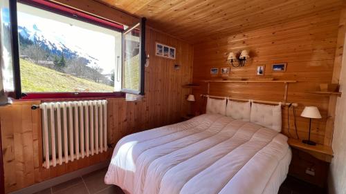 - une chambre avec un lit dans une pièce en bois dotée d'une fenêtre dans l'établissement LA CLUSAZ avec TERRASSE, à La Clusaz