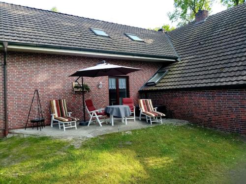 un patio con tavolo, sedie e ombrellone di Ferienwohnungen Evers 55181 a Stallbrüggerfeld