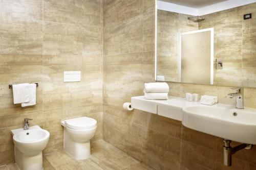 a bathroom with a sink and a toilet and a mirror at Hotel Italia in Cagliari