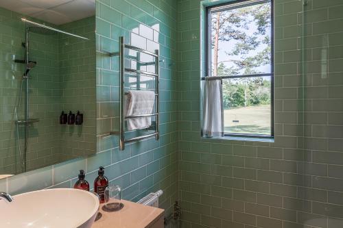 a green tiled bathroom with a sink and a window at Stufvenäs Gästgifveri in Söderåkra