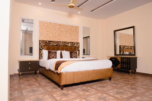 a bedroom with a large bed and a mirror at Hotel Mayfair in Lahore