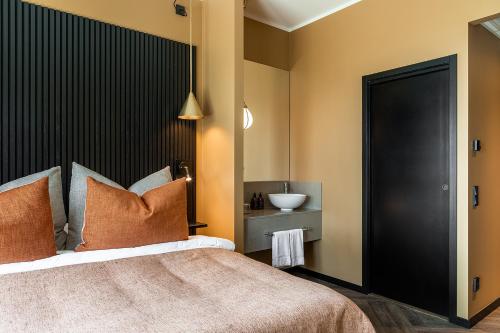 a bedroom with a bed with a black headboard and a sink at Stufvenäs Gästgifveri in Söderåkra