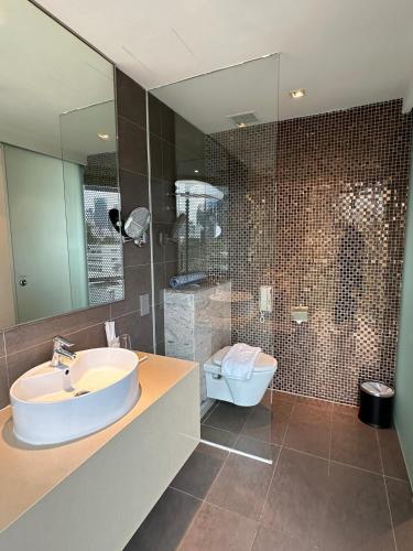 a bathroom with a sink and a toilet and a mirror at D'Hotel Singapore managed by The Ascott Limited in Singapore