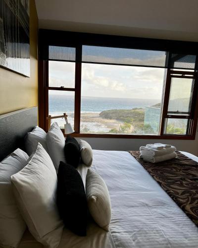 a bedroom with a bed with a view of the ocean at Points South By The Sea in Apollo Bay