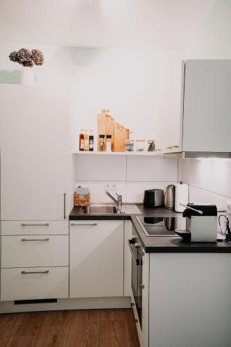a kitchen with white cabinets and a sink at Gemütliche Ferienwohnung mit direkter Innenstadtlage in Bingen am Rhein