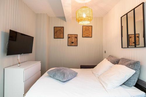 - une chambre avec un lit blanc et une télévision murale dans l'établissement Sublime studio rénové - Cannes Meynadier, à Cannes